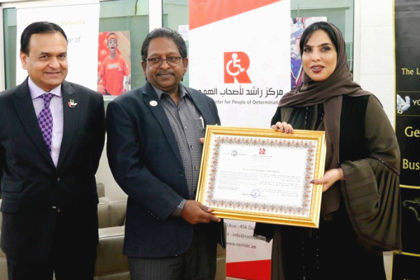 Prof. Christopher Abraham, Professor and Head of Campus (Dubai) at SP Jain School of Global Management, (centre) receives a token of appreciation from Her Excellency Ms. Mariam Othman, Founder and CEO of Rashid Centre for people of determination (right) in the presence of Dr. Tariq Nizami, Founder & CEO of CEO Clubs Network (left)