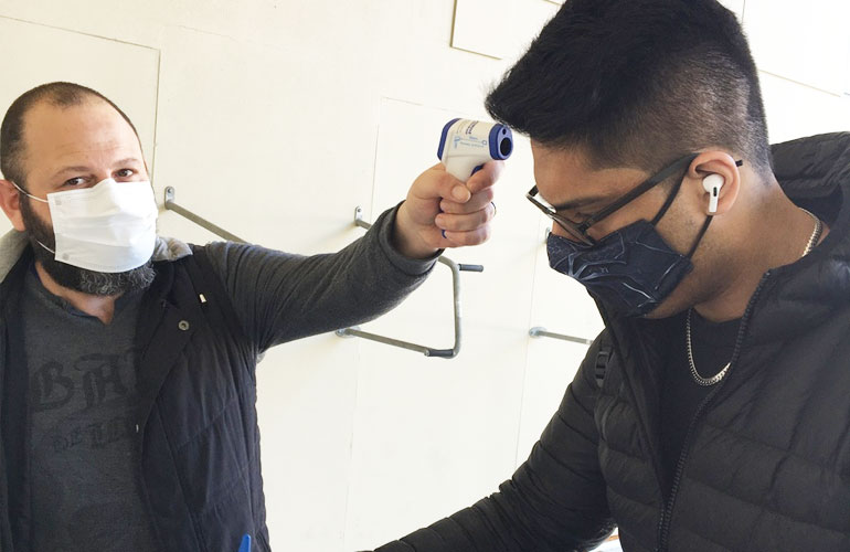 A student gets his temperature screened and recorded before entering the campus 